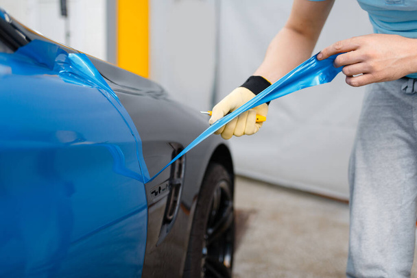 Male car wrapper hands installs protective vinyl foil or film on vehicle door. Worker makes auto detailing. Automobile paint protection, professional tuning - Φωτογραφία, εικόνα