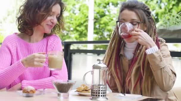 2人の若い女性の友人は春の日の間に屋外のコーヒーショップで一緒に昼食休憩をしています - 映像、動画