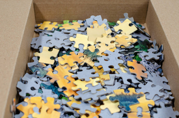 unsolved puzzle with pieces folded into a square cardboard box, - Foto, imagen