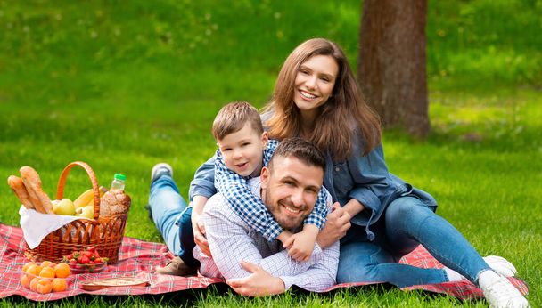 Glückliche Familie beim Picknick. Mama und Papa verbringen mit ihrem Sohn gemeinsame Zeit im Wald - Foto, Bild