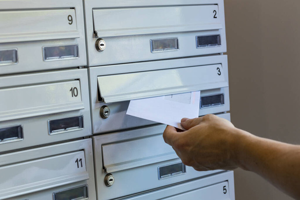 Ein Postbote wirft Pakete in Briefkästen - Foto, Bild