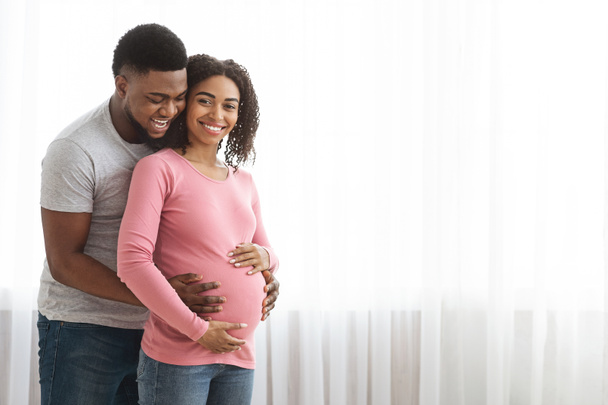 Cheerful black man touching his pregnant wife belly - Foto, imagen