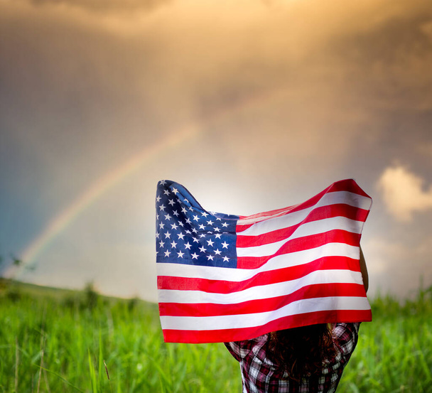 虹の空独立記念日にアメリカ国旗を掲揚する女性  - 写真・画像
