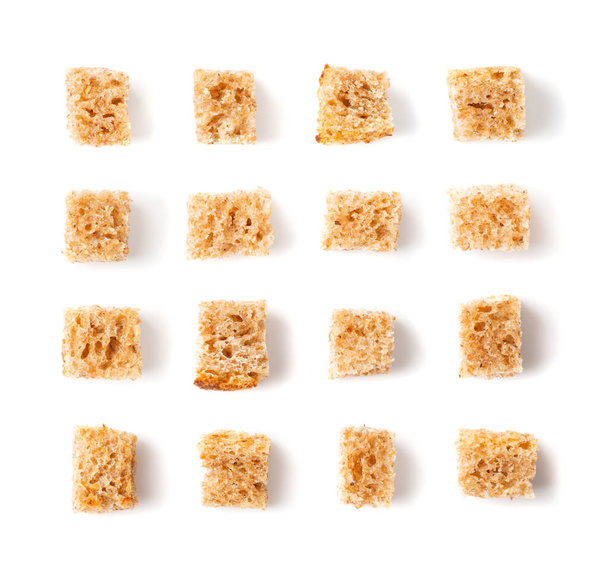Set of homemade rye bread croutons isolated on white background top view. Crispy bread cubes collection, dry rye crumbs, rusks, crouoton or brown roasted crackers cube pattern - 写真・画像