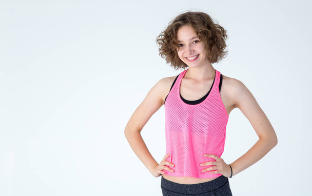 Happy young woman in pink shirt for fitness on gray background. Studio shot. - Zdjęcie, obraz