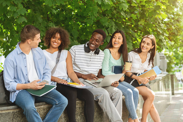 Grupa wielokulturowych studentów siedzących na dziedzińcu uczelni, studiujących razem - Zdjęcie, obraz