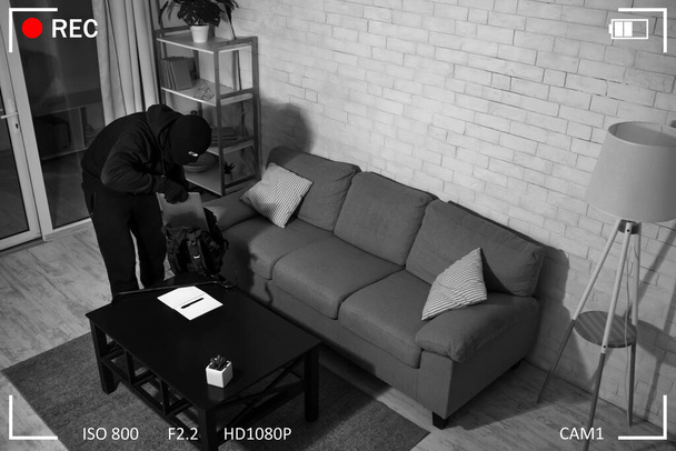 Delincuente irrumpiendo en un apartamento u oficina robando laptop
 - Foto, Imagen