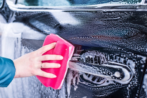 Girl cleaning automobile with sponge at car wash, car washing - Foto, imagen