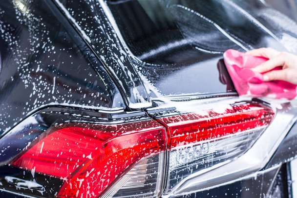 Chica de limpieza de automóviles con esponja en el lavado de coches, lavado de coches
 - Foto, imagen