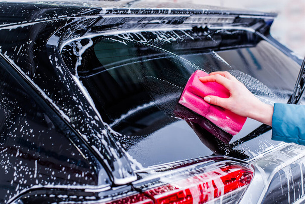 Girl cleaning automobile with sponge at car wash, car washing - Foto, Bild