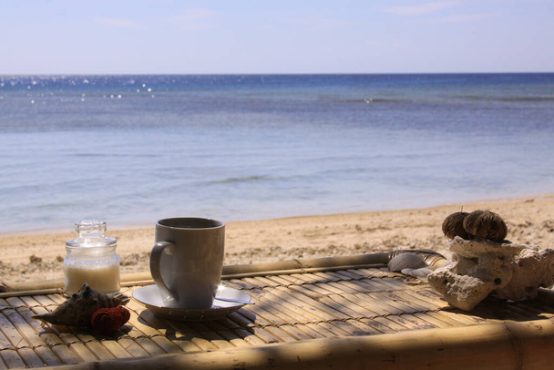 Καφές, ζάχαρη, κέλυφος και κοράλλι στο τραπέζι για ηλιόλουστη τροπική παραλία στο φως της ημέρας, στο νησί Gili Air, Lombok, Ινδονησία - Φωτογραφία, εικόνα