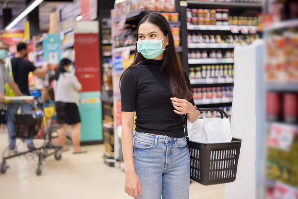 woman with face mask is shopping clothes in Shopping center  - Фото, изображение