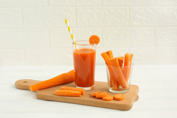 Copo de suco de cenoura e cenoura fresca na placa de corte
 - Foto, Imagem