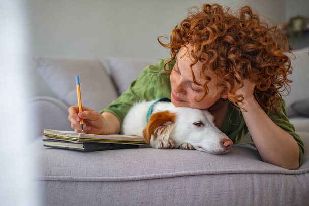Woman working at home. Freelance working. Young afro-american woman sitting with her pet dog and study at home. Woman working from home in the company of her puppy - Photo, image