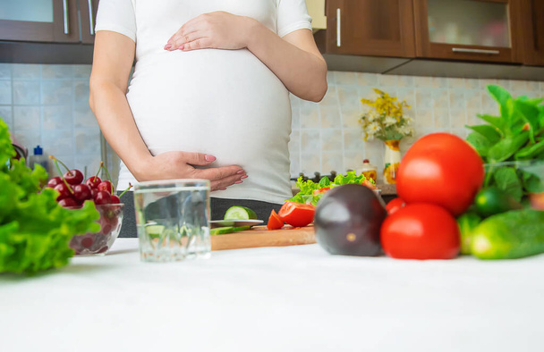 A pregnant woman eats vegetables and fruits. Selective focus. Food. - Фото, изображение