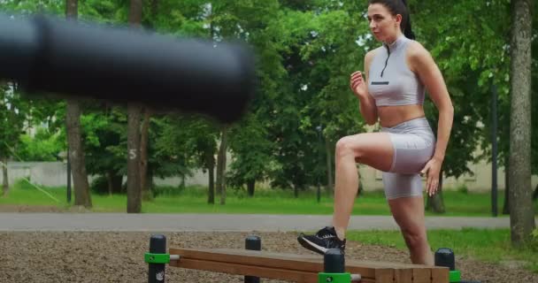 公園の若い女性は夏にスポーツウェアのベンチで厳しい肺を実行します。公園内の陸上競技白人女性の列車. - 映像、動画
