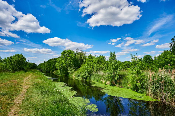 Kék és felhős ég egy kis patak felett a környező vidéken Berlin, Németország. - Fotó, kép