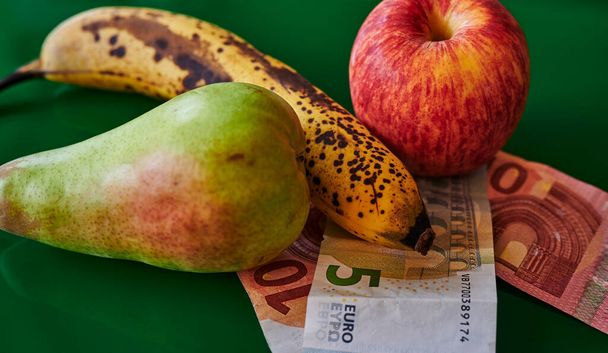 Meyve, yeşil arka planda Avrupa banknotlarıyla yan yana yatar. - Fotoğraf, Görsel