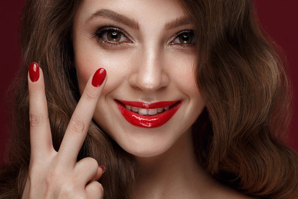 Beautiful girl with a classic make up, curls hair and red nails. Manicure design. Beauty face. - Photo, image
