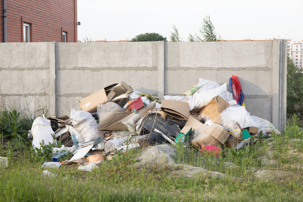 Montón de basura en un campo cerca de casas residenciales
 - Foto, imagen