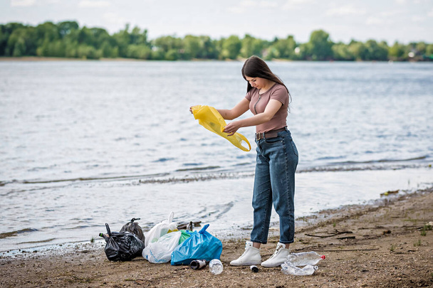 girl collects trash on the beach. girl cleans the beach of garbage - Valokuva, kuva