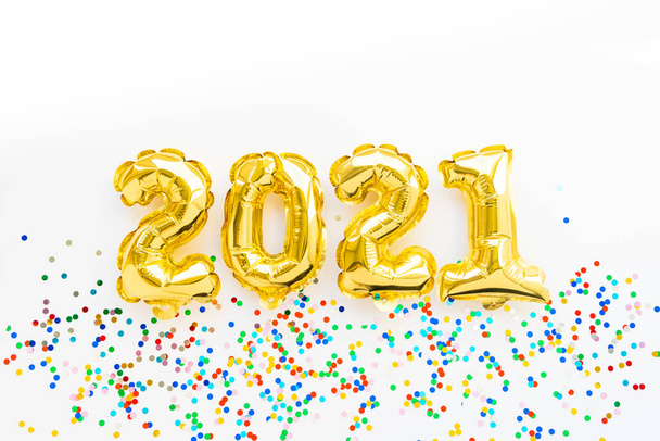 Happy New year 2021 celebration. Gold foil balloons numeral 2021 and confetti on white background. Flat lay - Foto, Imagem