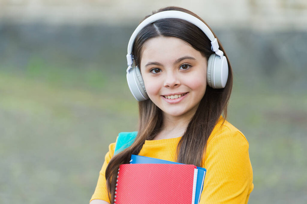 Check out new music. Happy child listen to music outdoors. Little kid in headphones hold printed music. Music school and education. New technology. Modern life. Musical knowledge that matters - Valokuva, kuva