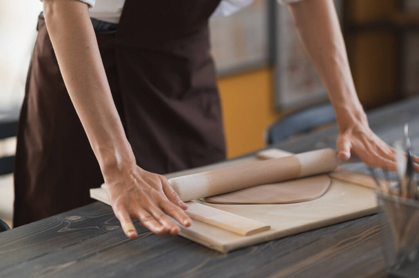 Nainen kädet flatting pala savea makaa kangas käyttäen puinen valssaustappi keraaminen studio. - Valokuva, kuva