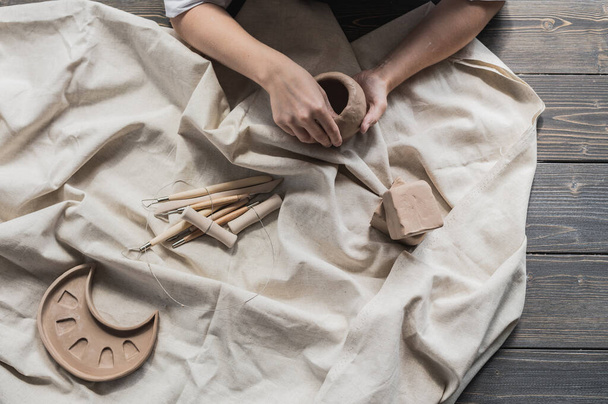 Female potter shaping piece of clay at the table. Woman making ceramic item. Pottery working, handmade and creative skills at arts studio. - Φωτογραφία, εικόνα