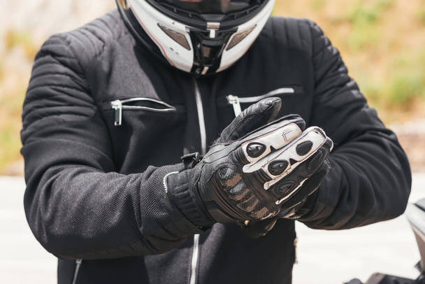 Motorcu bisiklete binmek için eldivenlerini giyer. - Fotoğraf, Görsel