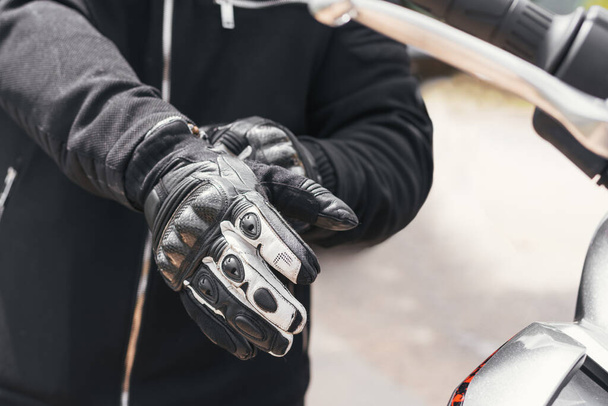 biker puts on his gloves to ride his bike - Foto, afbeelding