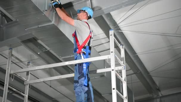 Trabajador de construcción en andamio de fijación y atornillado de piezas metálicas del sistema de conductos de ventilación
.  - Metraje, vídeo
