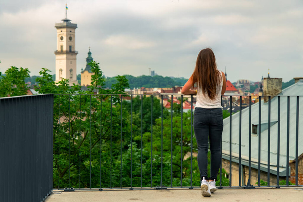 destinazione di viaggio visita della carta da parati poster concetto di ragazza attraente torna alla fotocamera godere dalla città vecchia europea dal punto di vista superiore in Ucraina Lviv - Foto, immagini