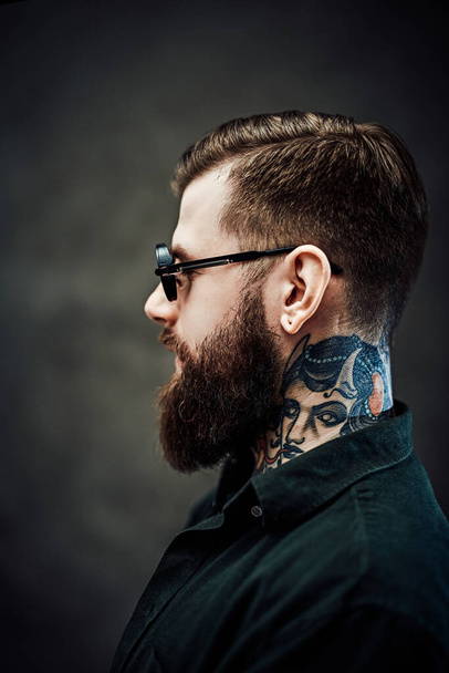 Портрет крутого бородатого мужчины в солнцезащитных очках на темном фоне
 - Фото, изображение