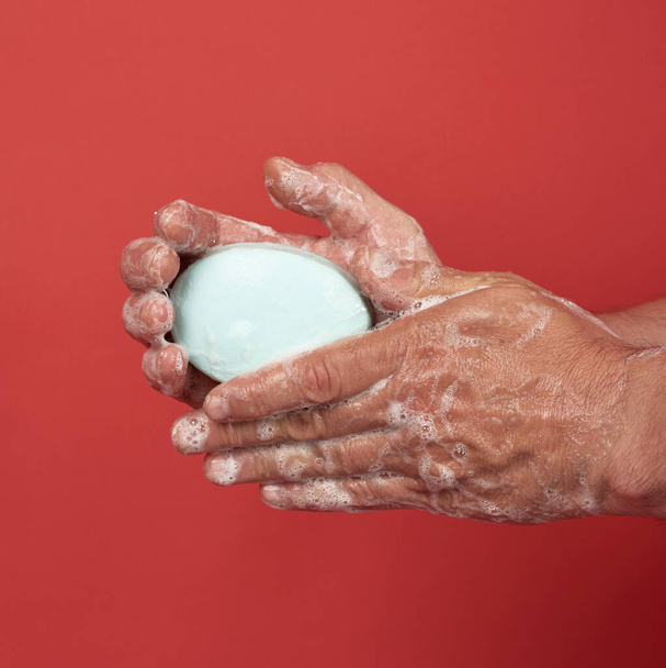 dos manos masculinas en una espuma jabonosa blanca, higiene corporal, fondo rojo
  - Foto, imagen