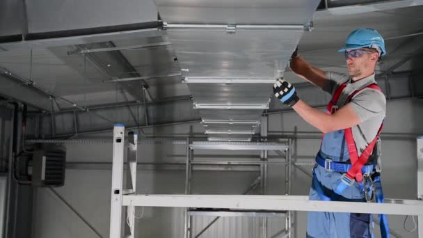 Caucasico maschio aria condizionata professionale montaggio condotto di ventilazione sul soffitto di interni di grande edificio.  - Filmati, video