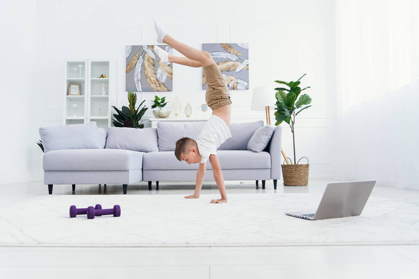 Teen boy doing hands standing exercises at cozy living room. - Fotoğraf, Görsel
