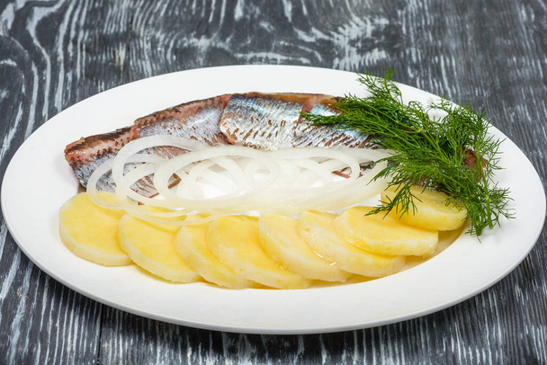 Exquisite starter of salted herring with boiled potatoes and pickled onions with herbs in restaurant serving - Foto, imagen