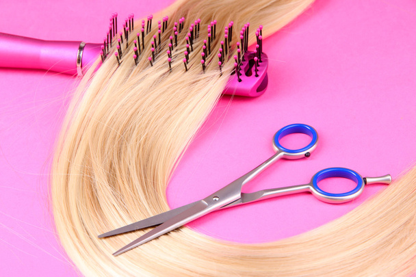 Long blond hair with hairbrush and scissors on pink background - Fotografie, Obrázek