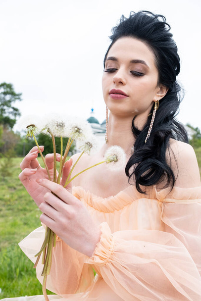 Young girl in evening dress with a bouquet of dandelions - Foto, Bild