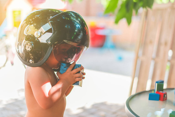 kid with a pilot's helmet playing with a rubik's cube with the background out of focus - Photo, Image