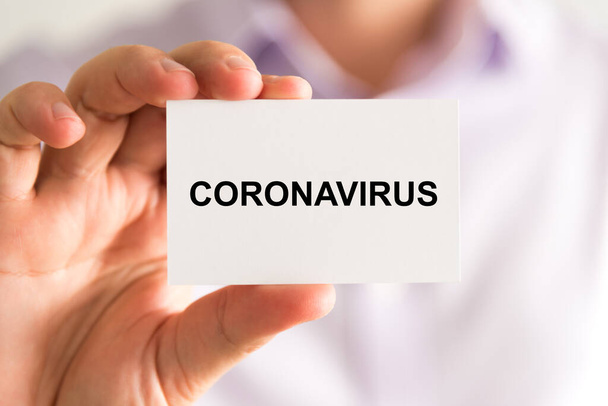 Close-up op zakenman met een kaart met tekst Coronavirus, business concept beeld met zachte focus achtergrond - Foto, afbeelding