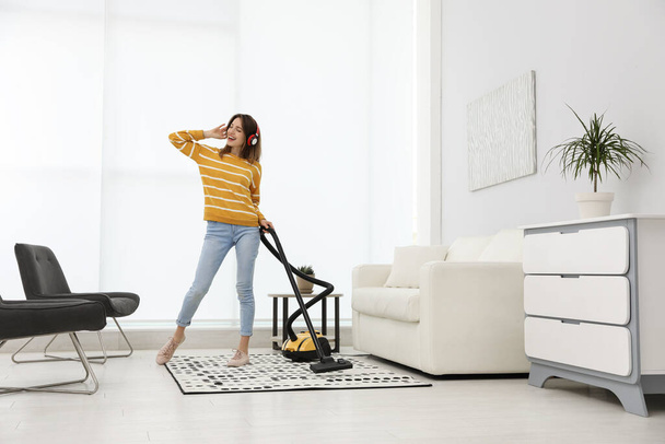Young woman having fun while vacuuming at home - Foto, Imagen