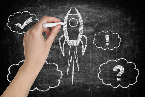 Business startup concept. Woman drawing rocket on chalkboard, closeup - 写真・画像