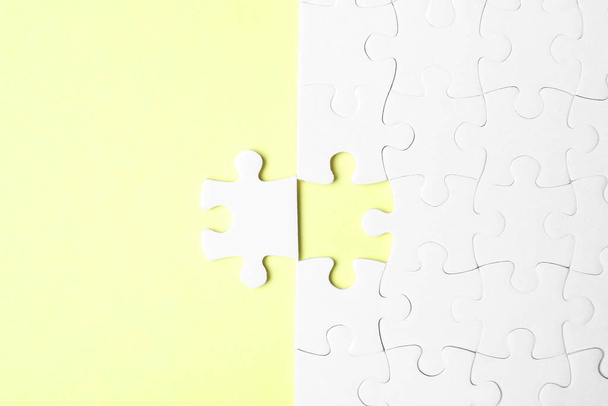 Blank white puzzle with separated piece on yellow background, flat lay - Φωτογραφία, εικόνα