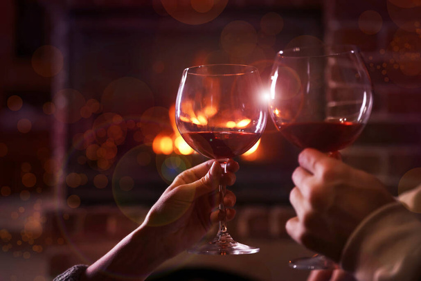 Bájos pár egy pohár borral a kandalló közelében, közelről. Téli vakáció - Fotó, kép