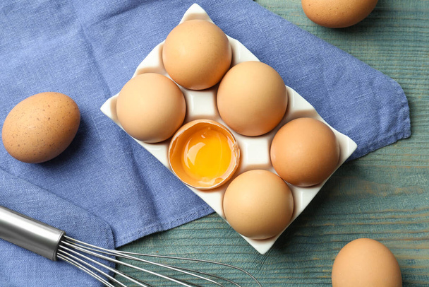Composición plana con huevos de pollo sobre una mesa de madera azul
 - Foto, Imagen