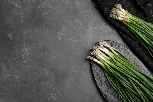 Fresh green spring onions on grey table, flat lay. Space for text - Фото, изображение