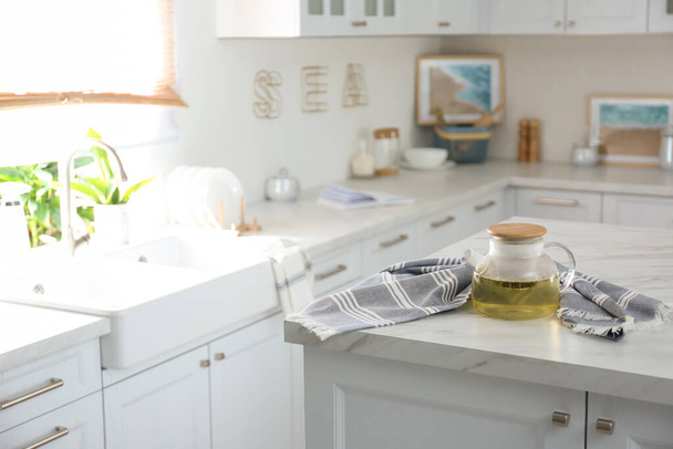 モダンなキッチンで白い大理石のテーブルの上にティーポットとタオル。インテリアデザイン - 写真・画像