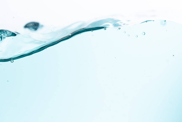 Surface of the blue water waves splash on a white background - Foto, imagen